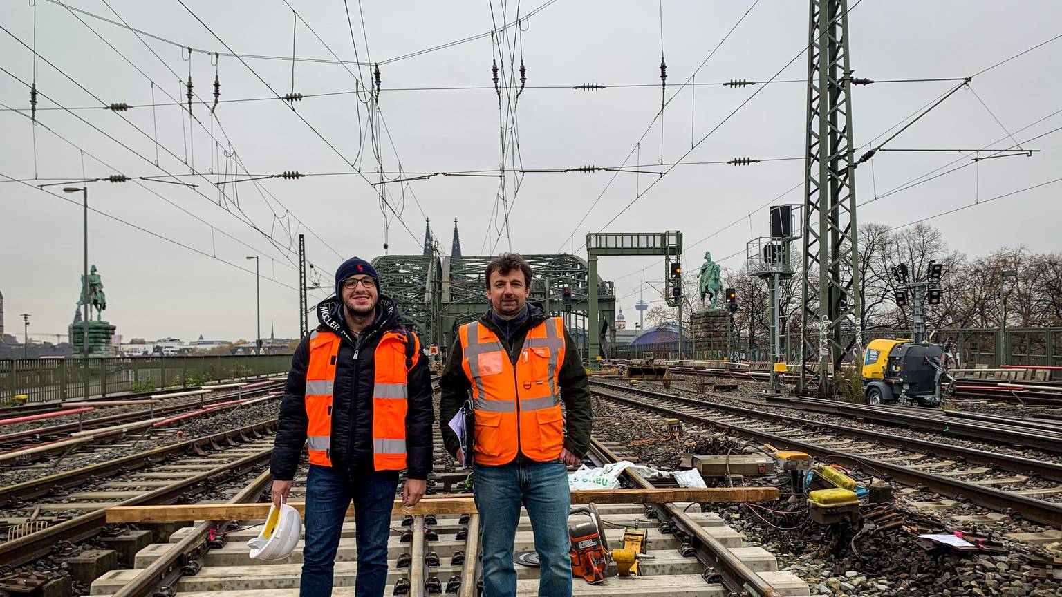 Zwei Männer stehen im Gleisbett auf der Hohenzollernbrücke: Projektleiter Naim Selimovic (links) und Bauüberwacher Miroslaw Radacz. Seit einigen Tagen erneuert die Deutsche Bahn Weichen im Bahnhof Köln Messe/Deutz. Während der Arbeiten können zwei der sechs Gleise auf der Brücke nicht befahren werden.