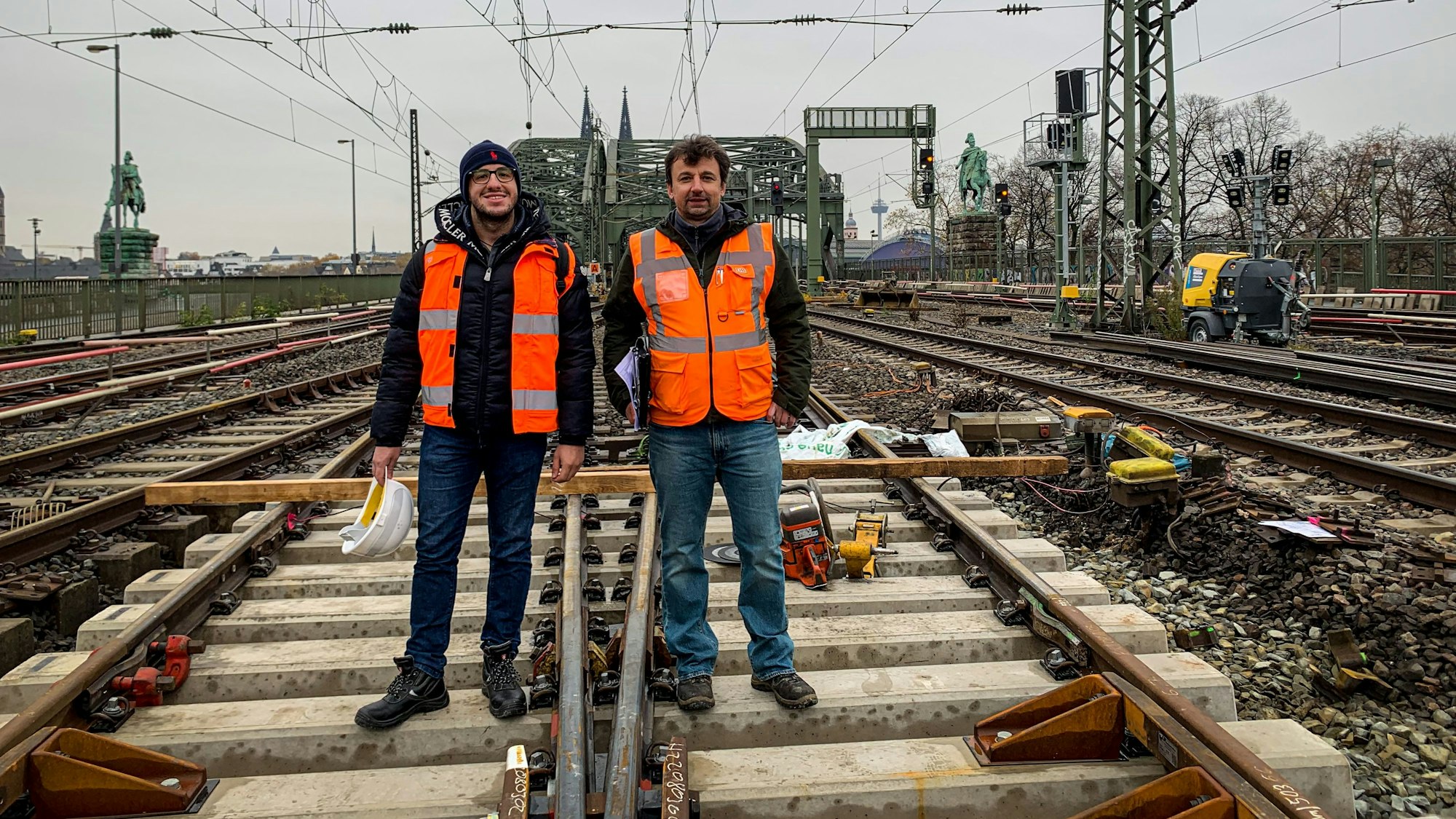Zwei Männer stehen im Gleisbett auf der Hohenzollernbrücke: Projektleiter Naim Selimovic (links) und Bauüberwacher Miroslaw Radacz. Seit einigen Tagen erneuert die Deutsche Bahn Weichen im Bahnhof Köln Messe/Deutz. Während der Arbeiten können zwei der sechs Gleise auf der Brücke nicht befahren werden.