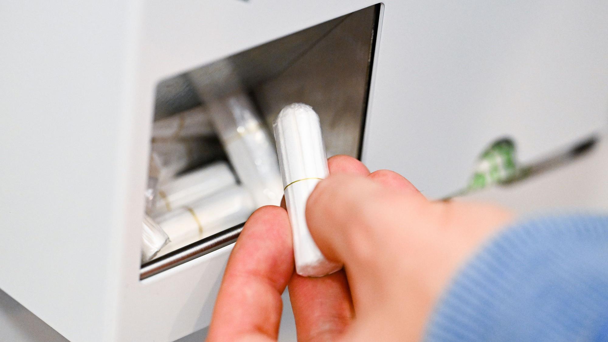 Eine Hand nimmt einen Tampon aus einem Tampon-Spender.