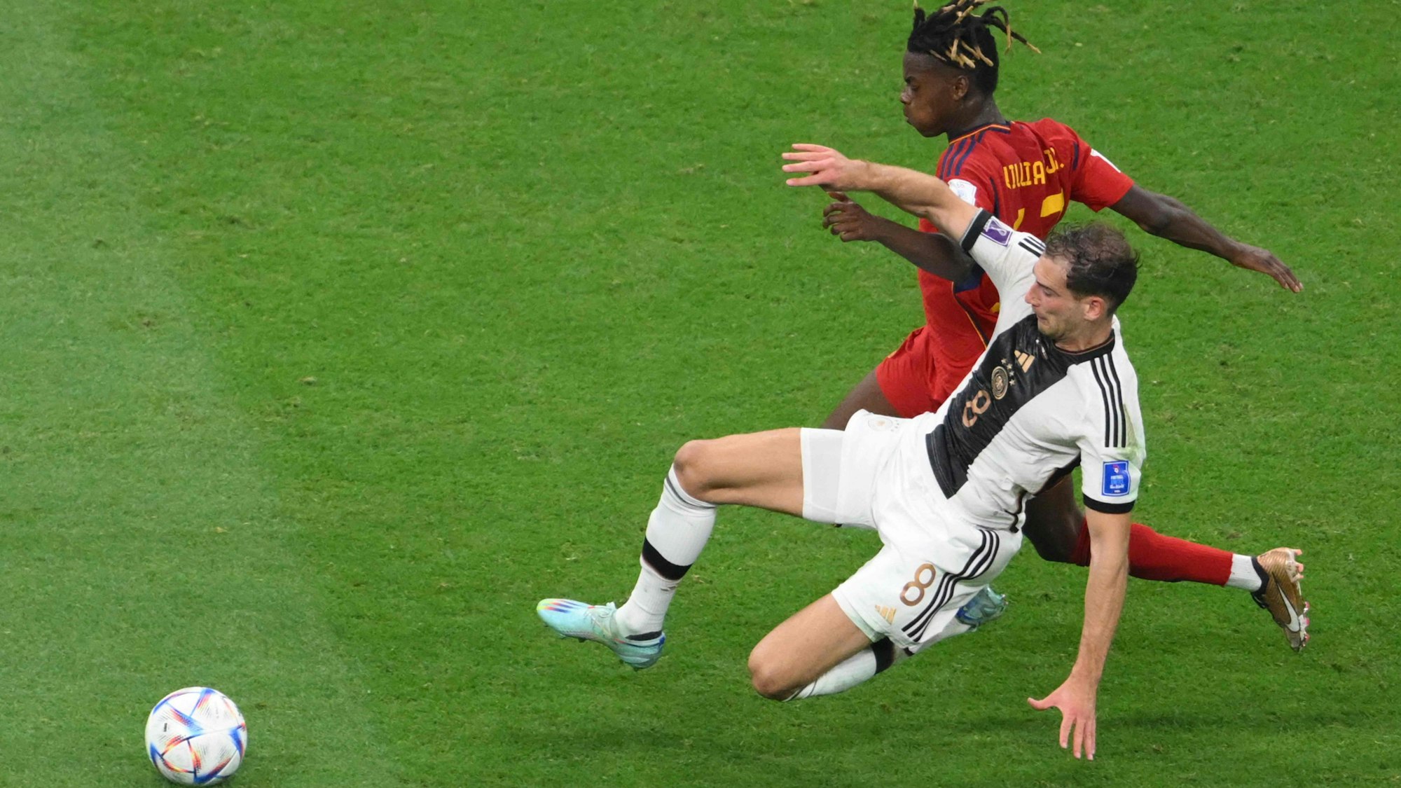 Der deutsche Mittelfeldspieler Leon Goretzka (r.) grätscht den Spanier Nico Williams ab. Goretzka trägt ein weißes Trikot und eine weiße Hose.