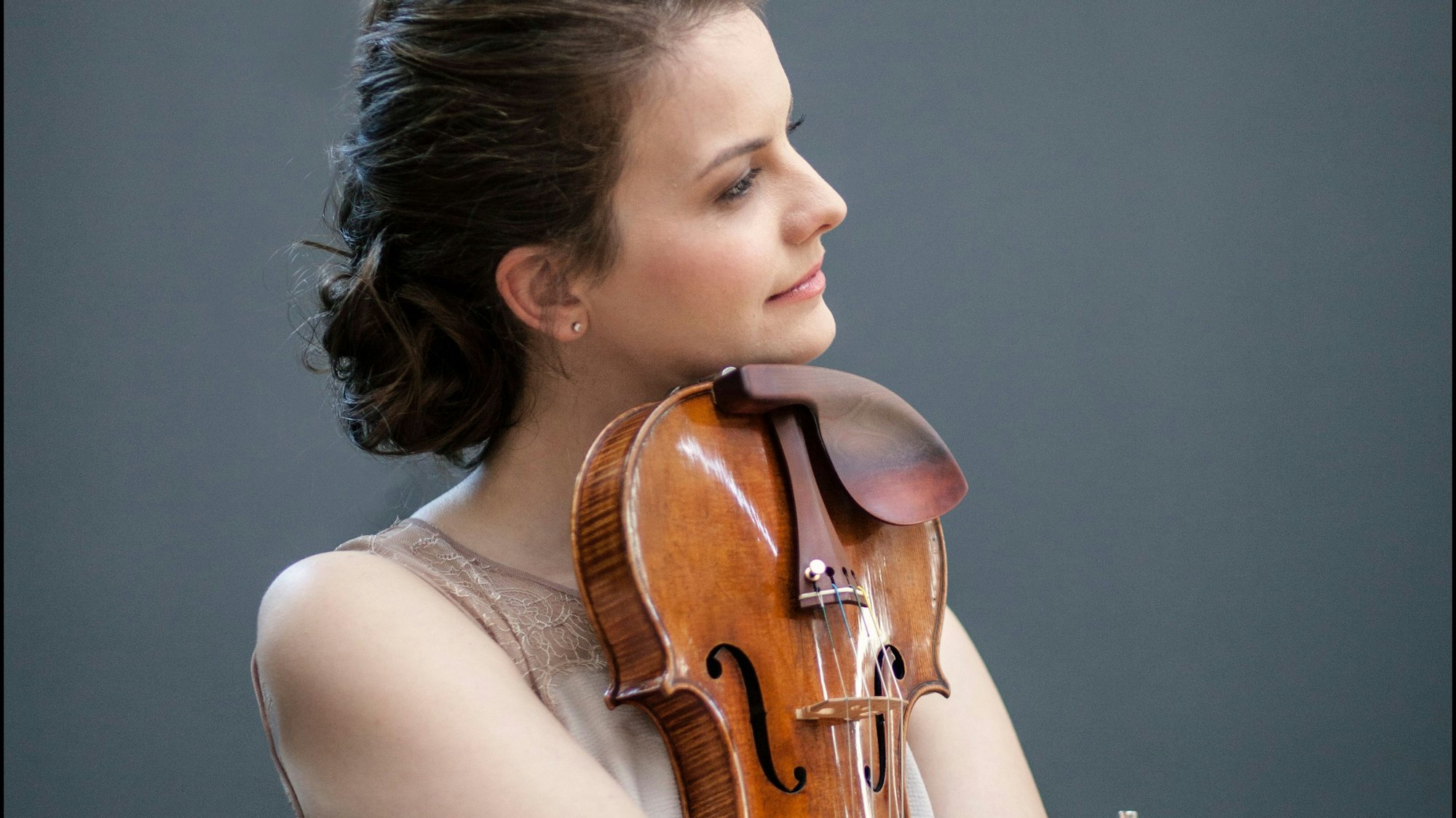 Violinistin Veronika Eberle hält ihre Geige eng an ihrem Körper und stützt sich mit ihrem Kinn auf sie.