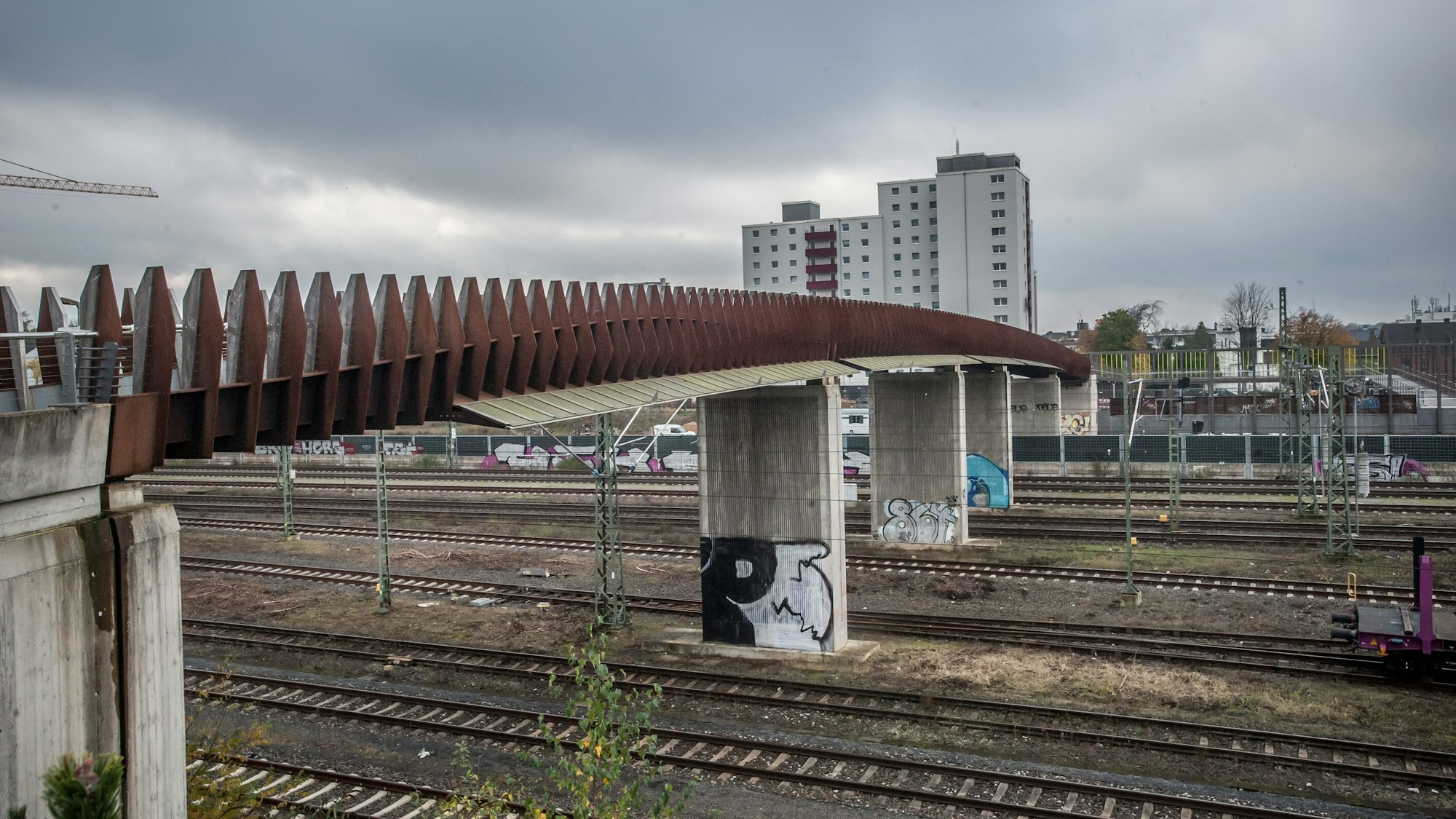 Die Campusbrücke und Bahngleise in Leverkusen-Opladen. Im Hintergrund ein Hochhaus.