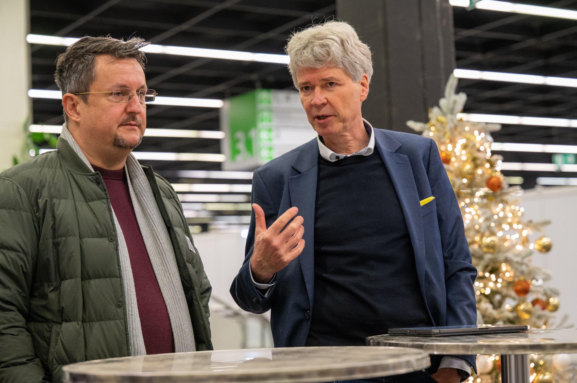 Marc Ruda und Harald Rau stehen in der Halle 3 der Koelnmesse.