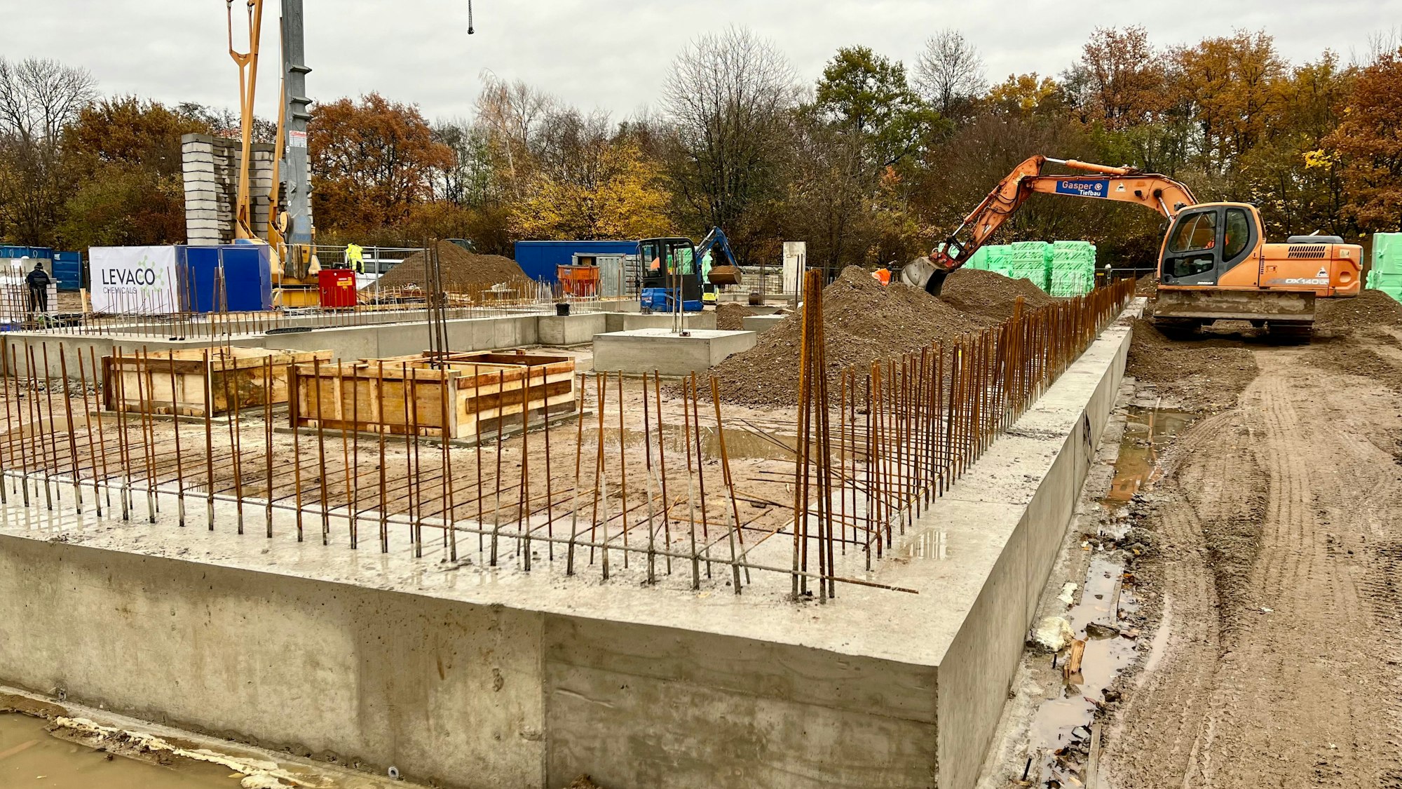 Aus dem Betonfundament der künftigen Levaco-Zentrale ragen stählerne Armierungen.Im Hintergrund ein Bagger