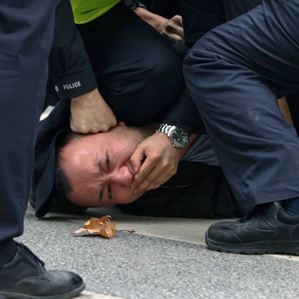 Polizisten halten am Sonntag einen Demonstranten während einer Demonstration auf einer Straße in Shanghai fest.