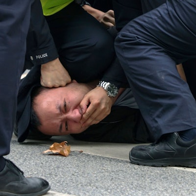 Polizisten halten am Sonntag einen Demonstranten während einer Demonstration auf einer Straße in Shanghai fest.