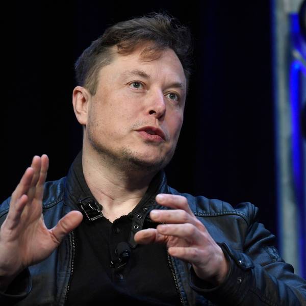 Elon Musk spricht auf einer Konferenz, er gestikuliert mit den Händen.