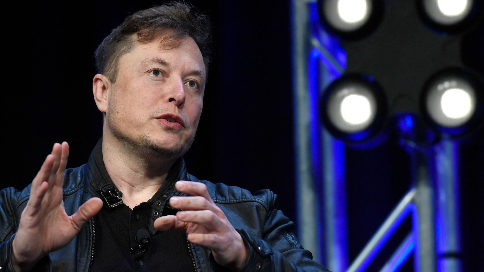 Elon Musk spricht auf einer Konferenz, er gestikuliert mit den Händen.