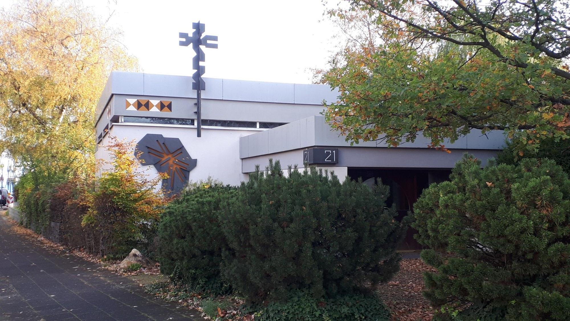 Das Bild zeigt einen Flachbau mit dem Symbol des Ordens der Weißen Väter und dem Umriss Afrikas aus Metall an der Außenwand.
