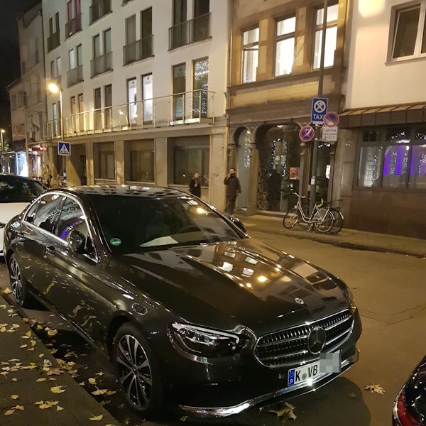 Ein schwarzer Mercedes steht am Straßenrand.