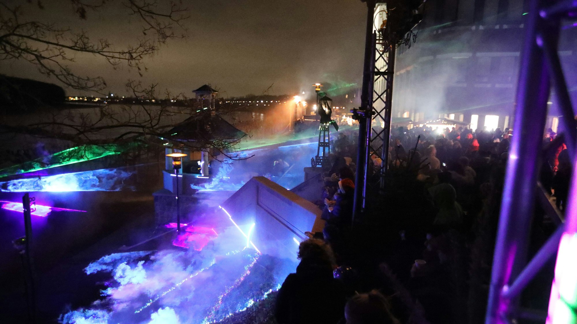 Das Porzer Rheinufer bei Nacht in lila und grünes Laserlicht getaucht.