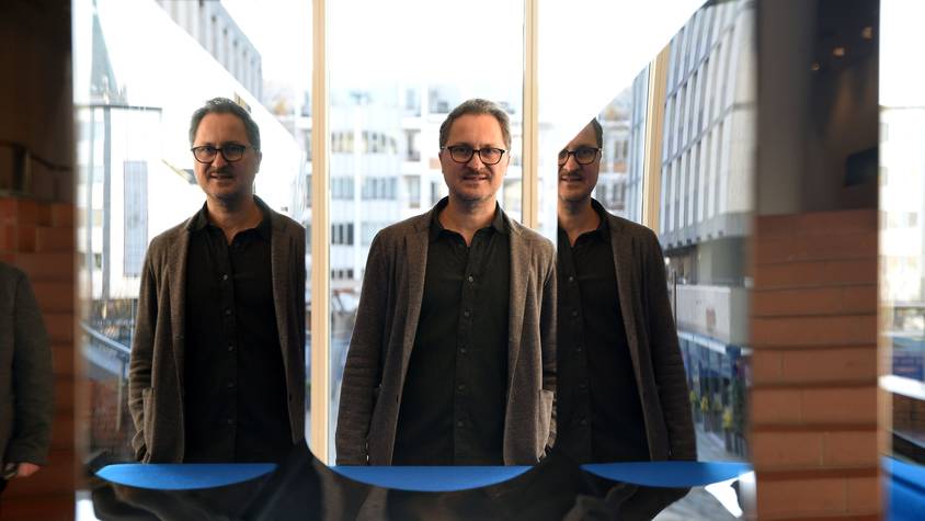 Yilmaz Dziewior steht vor einem Kunstwerk, das ihn zweifach spiegelt.