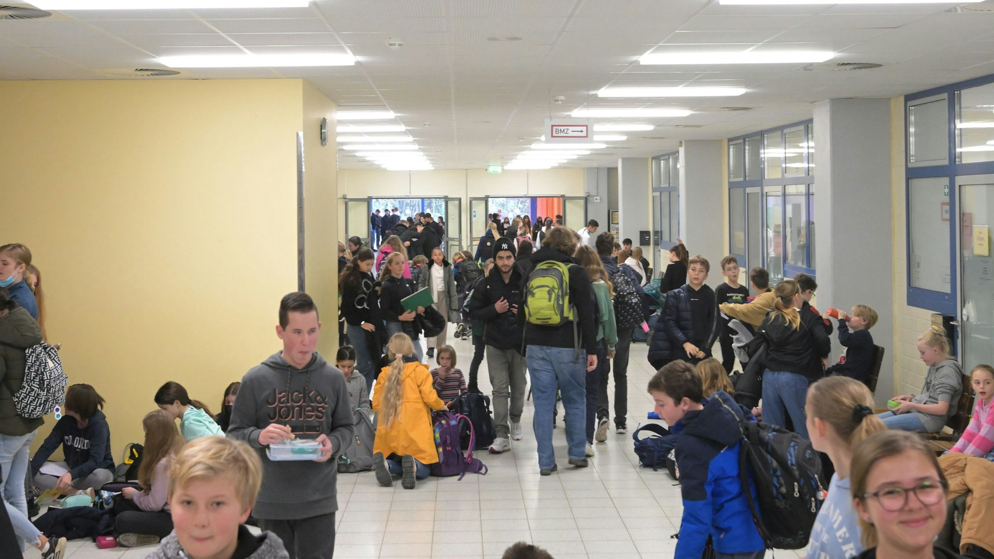 Schülerinnen und Schüler des Gymnasiums Herkenrath in Bergisch Gladbach sitzen in einem Gang.