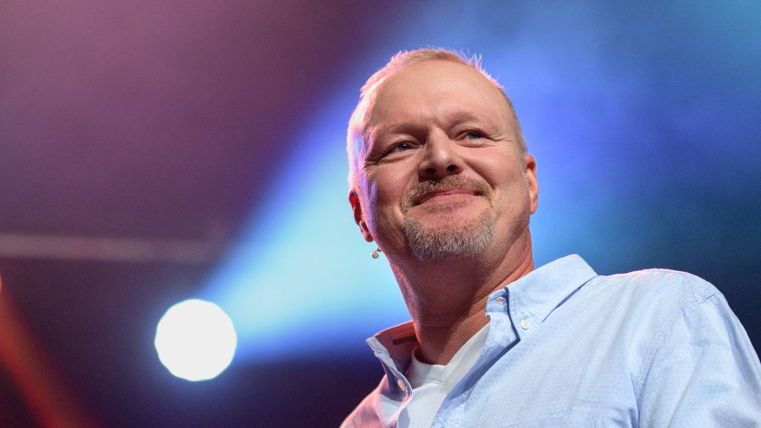Stefan Raab steht auf einer Bühne und schaut ins Publikum. Hinter dem Entertainer und „TV Total“-Moderator ist ein Scheinwerferlicht zu sehen. (Archivbild)