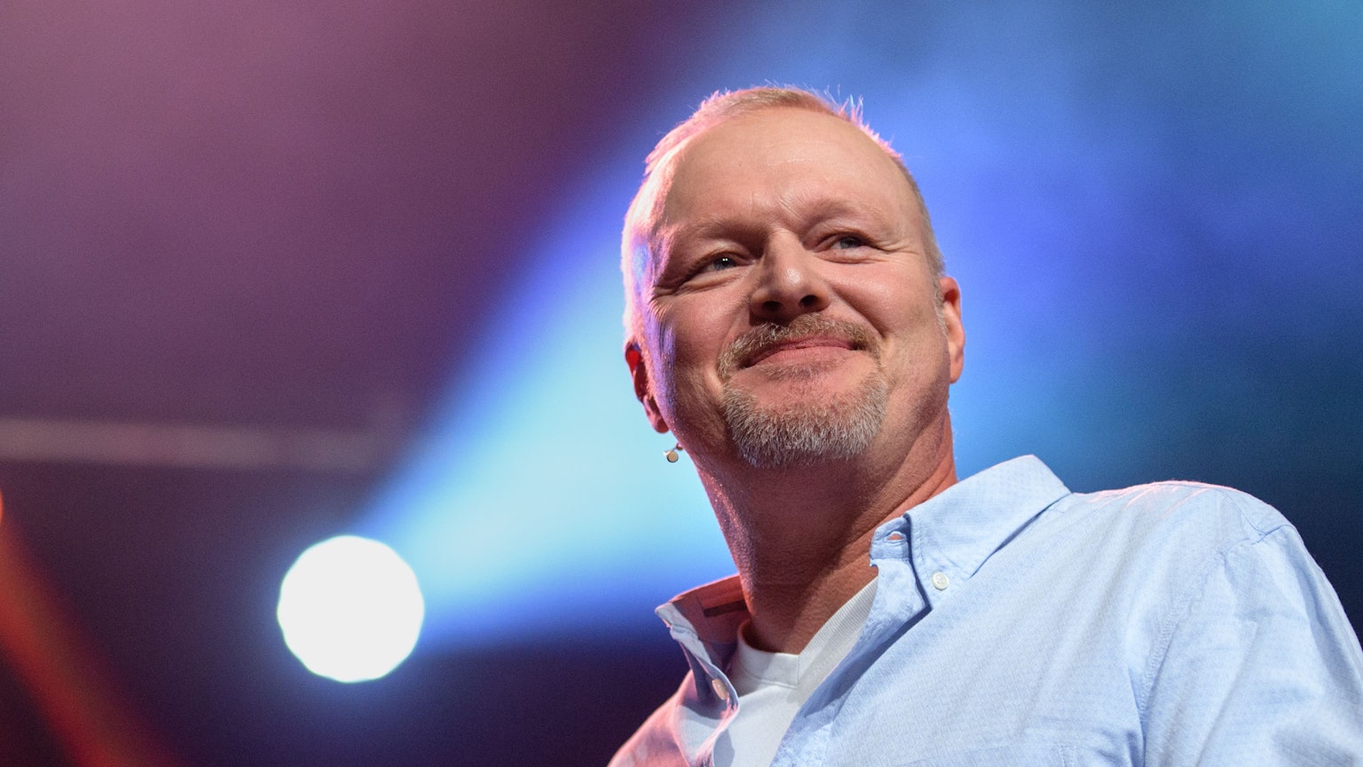 Stefan Raab steht auf einer Bühne und schaut ins Publikum. Hinter dem Entertainer und „TV Total“-Moderator ist ein Scheinwerferlicht zu sehen. (Archivbild)