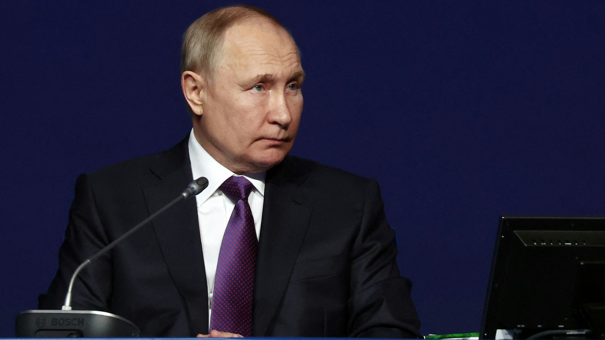 Der russische Präsident Wladimir Putin sitzt bei einer Konferenz an einem Tisch.