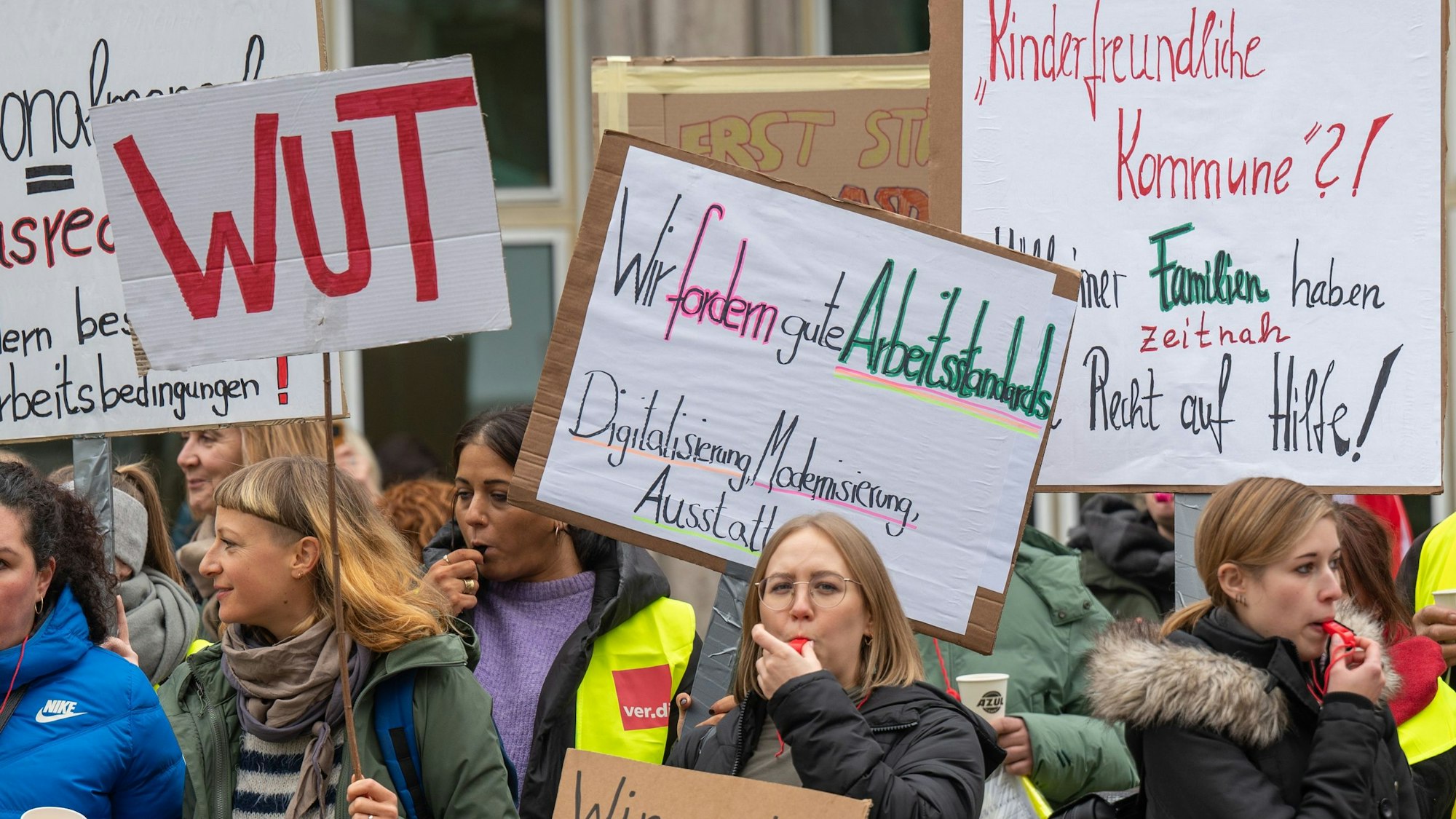 Menschen mit Plakaten in der Hand und Trillerpfeifen wollen erreichen, dass Kinder in Köln besser geschützt werden.
