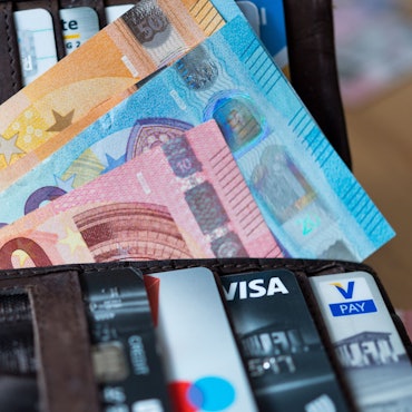 Banknoten und Bankkarten liegen in einer Geldbörse.