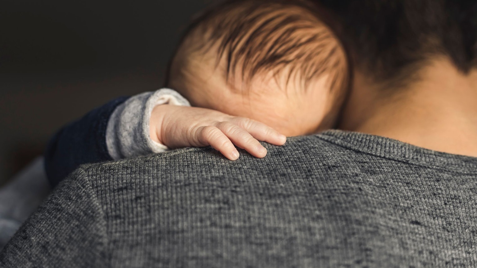 Ein Baby hat die Hand auf die Schulter des Vaters gelegt.