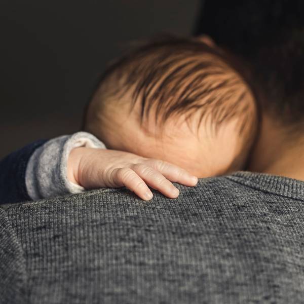Ein Baby hat die Hand auf die Schulter des Vaters gelegt.