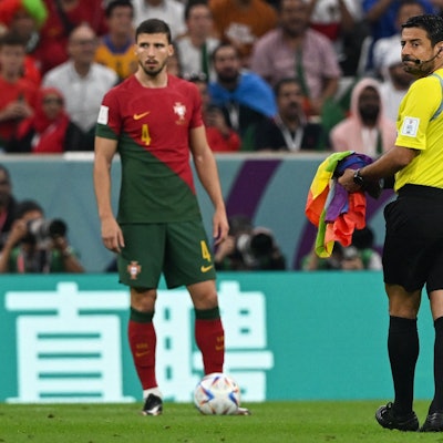 Beim Spiel Portugal gegen Uruguay hat ein Flitzer eine Regenbogenfahne vor den Füßen des Schiedsrichters fallen lassen. Der hebt sie auf und bringt sie an den Spielfeldrand.