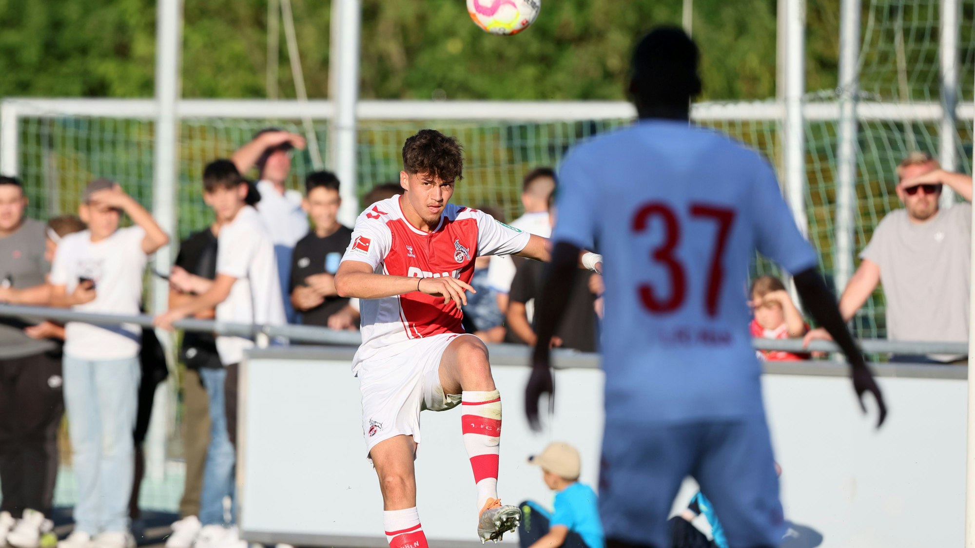 Ein Fußballspieler schlägt eine Flanke und schaut dem Ball hinterher.
