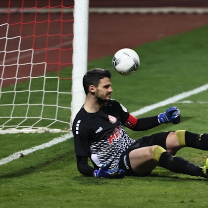 Ein Torwart sitzt auf dem Boden, der Ball ist rechts neben ihm zu sehen.