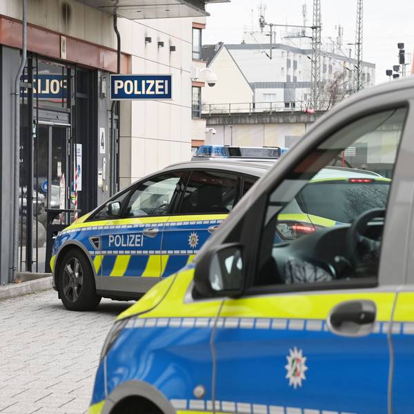 Zwei Polizeifahrzeuge stehen vor einer Polizeiwache.