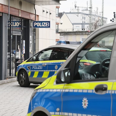 Zwei Polizeifahrzeuge stehen vor einer Polizeiwache.
