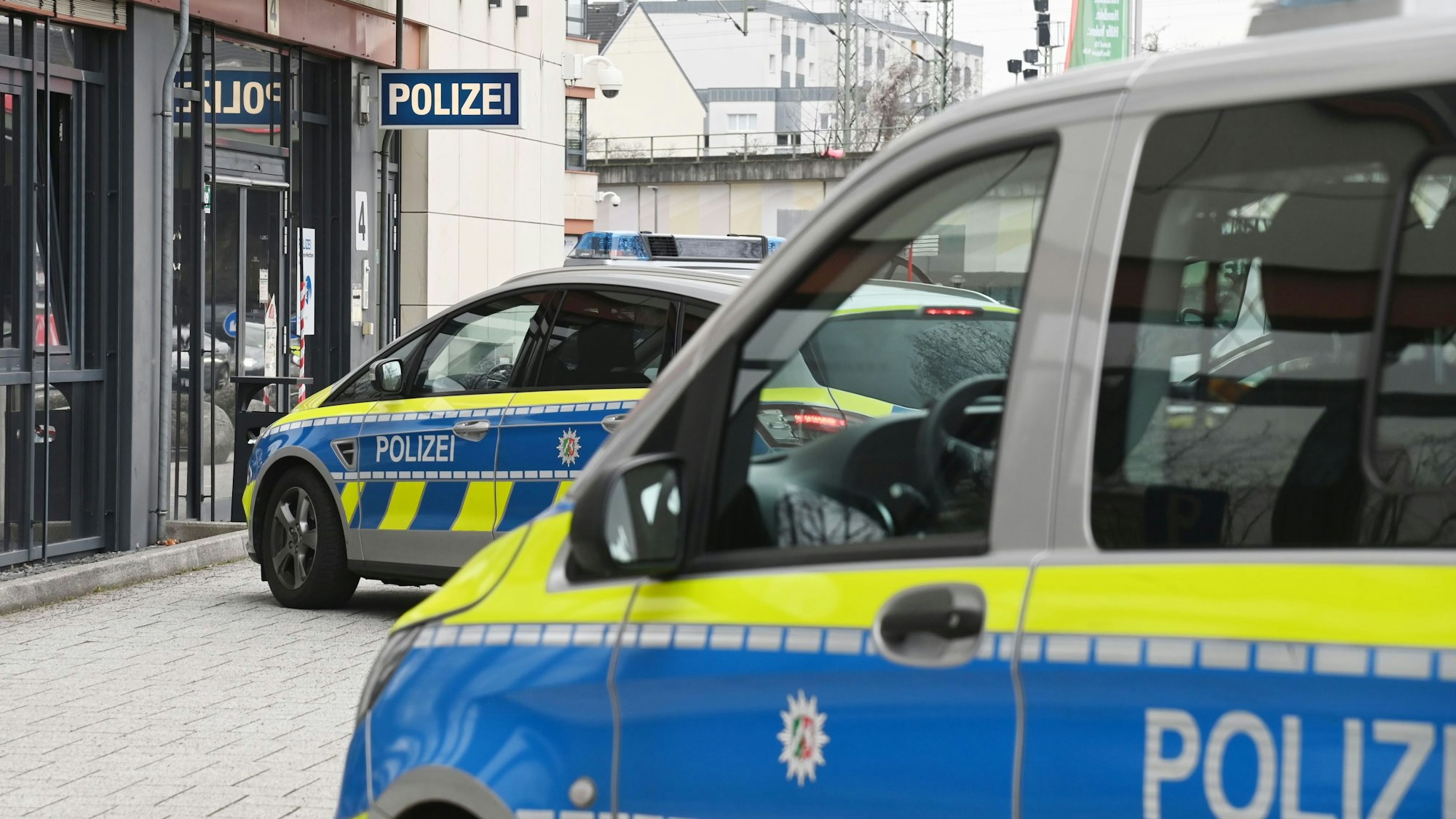 Zwei Polizeifahrzeuge stehen vor einer Polizeiwache.