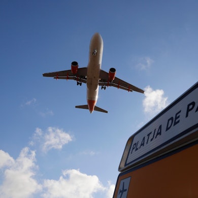 Palma: Ein Flugzeug überfliegt bei der Landung auf Mallorca ein Schild, das die Richtung nach Playa de Palma anzeigt. Auf einem Flug nach Mallorca haben fünf Deutsche einem Passagier das Leben gerettet.
