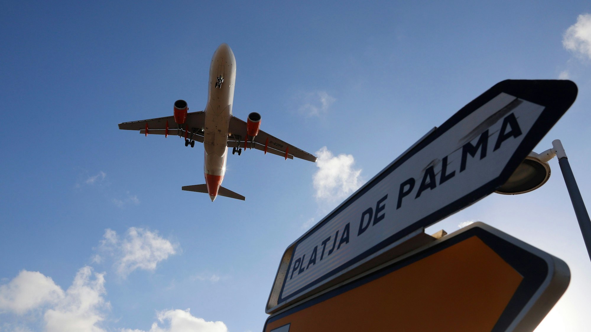Palma: Ein Flugzeug überfliegt bei der Landung auf Mallorca ein Schild, das die Richtung nach Playa de Palma anzeigt. Auf einem Flug nach Mallorca haben fünf Deutsche einem Passagier das Leben gerettet.
