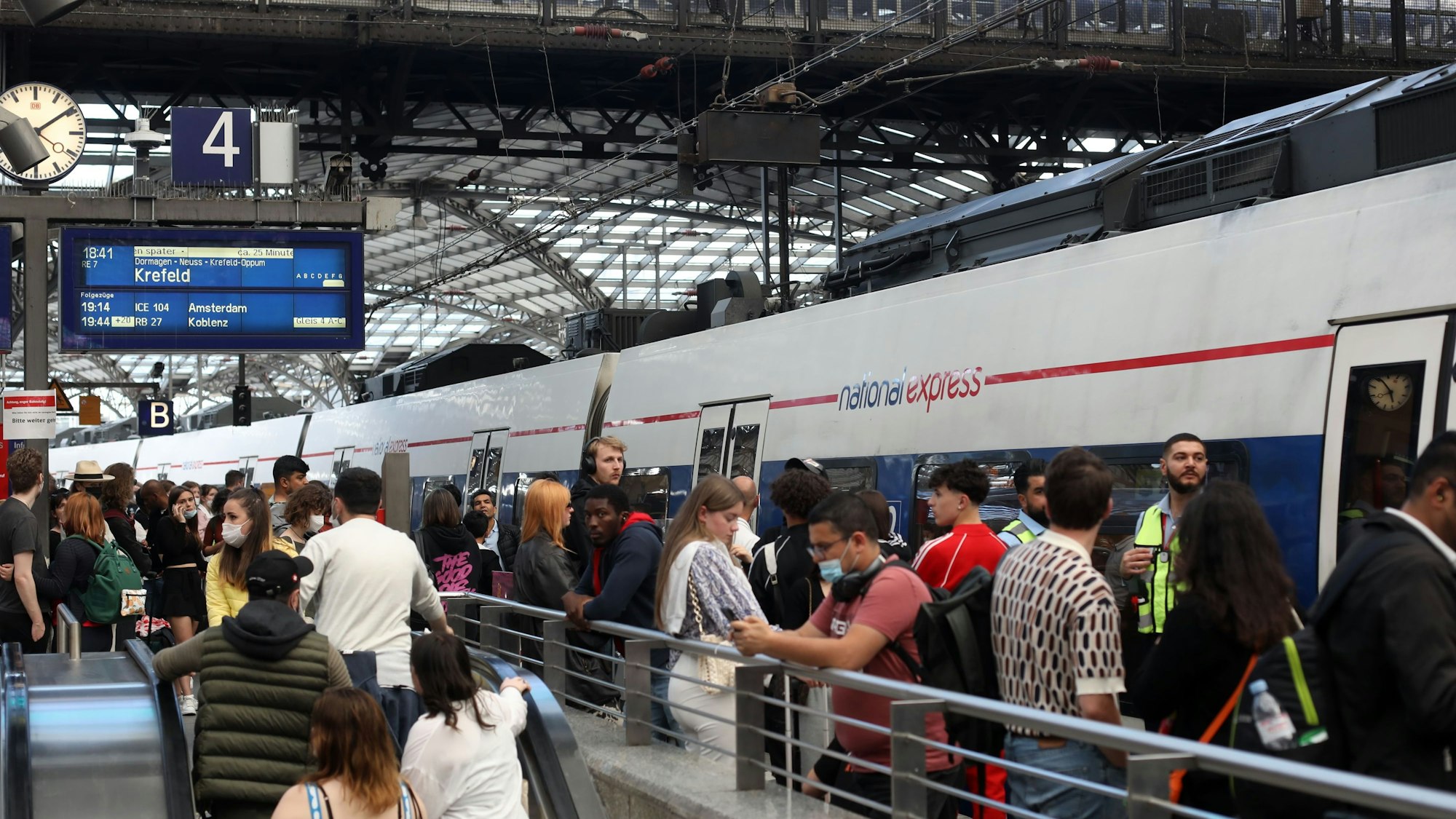 Fahrgäste warten auf Gleis 4 am Kölner Hauptbahnhof auf einen Zug von National Express. Einige Fahrgäste steigen aus, andere in den Zug ein. (Symbolbild)
