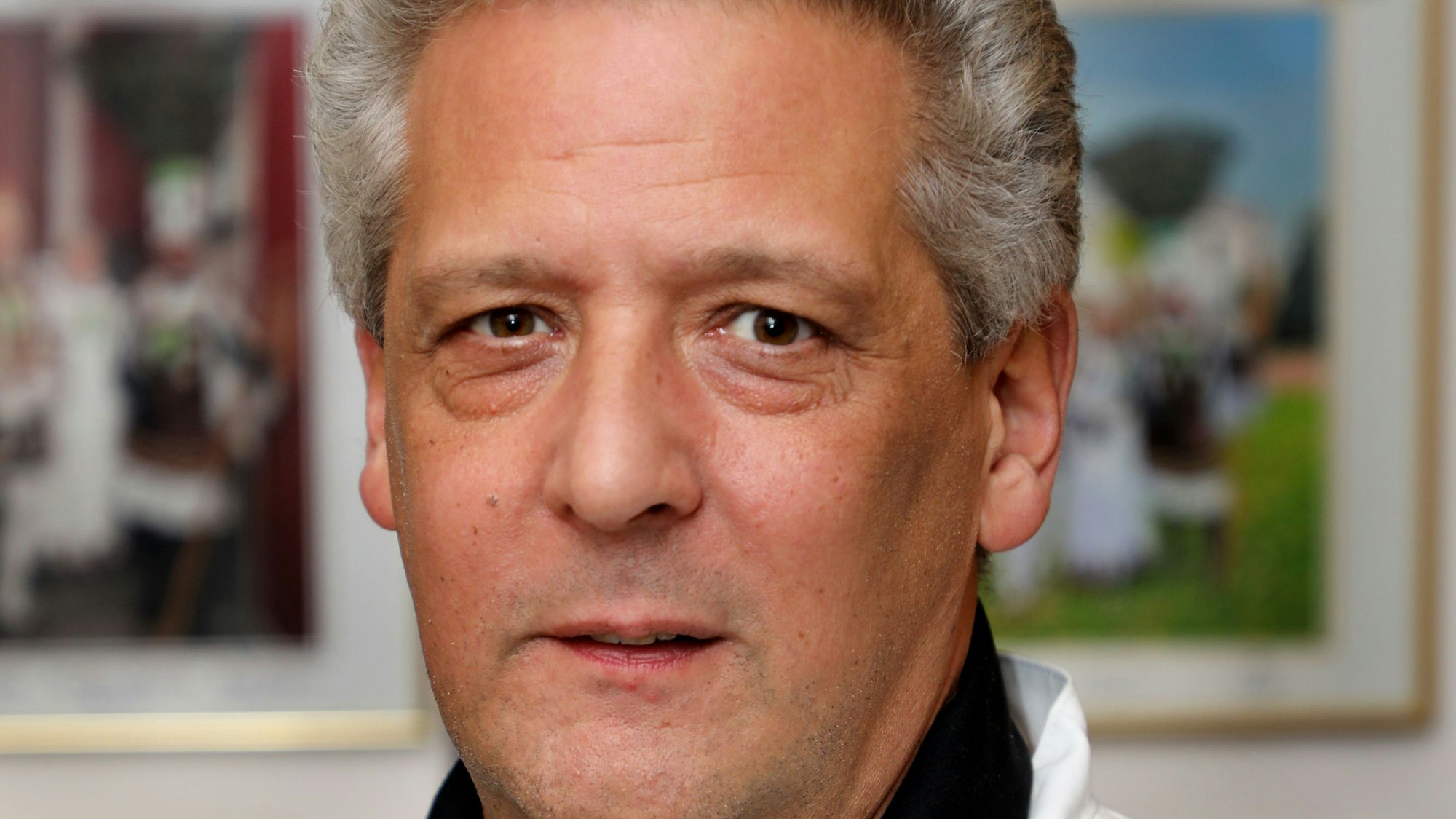Portrait von Udo Güldenberg. Er hat kurze graue Haare, trägt eine weiße Kochunifirm und ein schwarzes Halstuch.