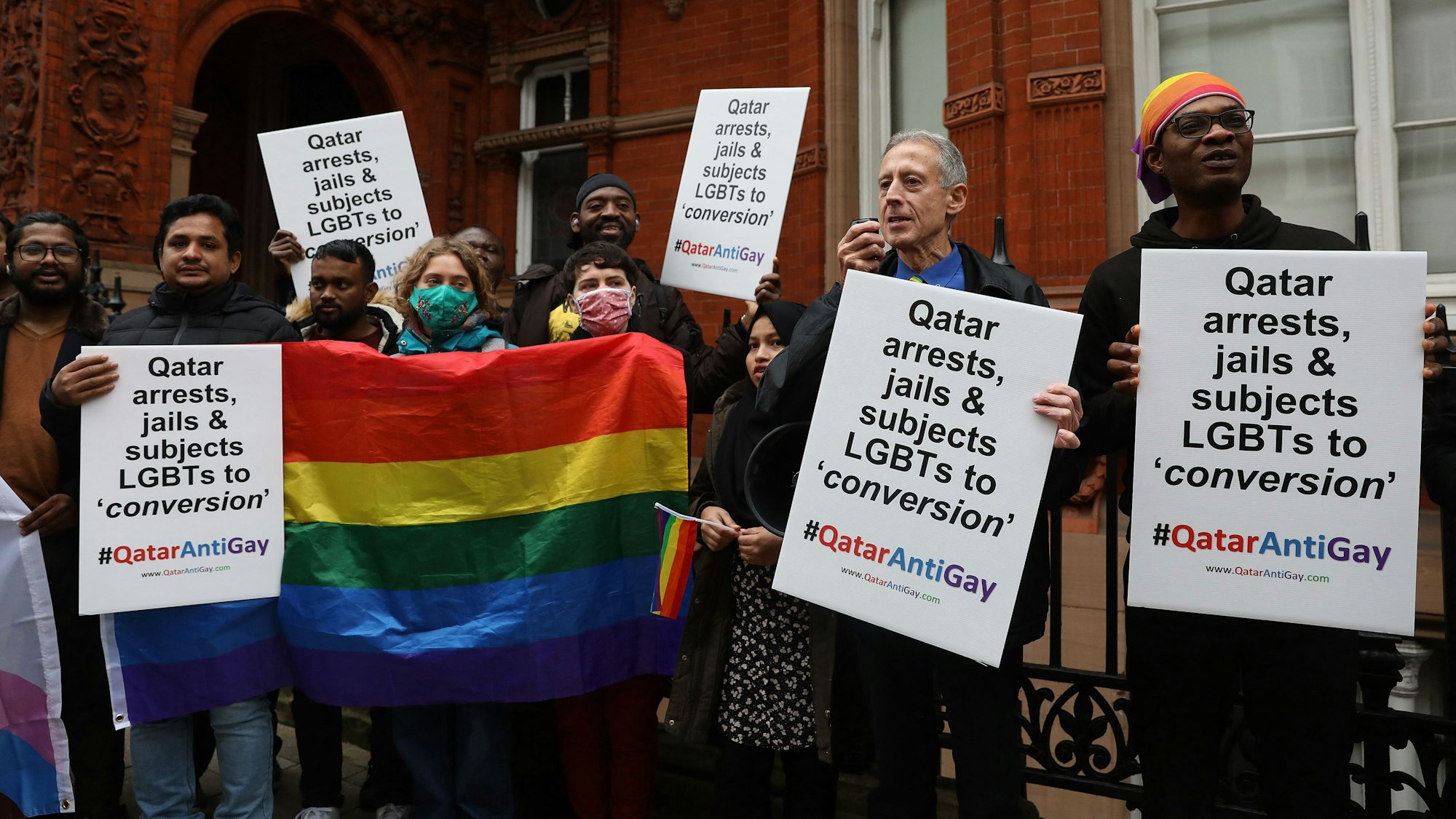 Vor der katarischen Botschaft in London protestieren Aktivisten gegen die Unterdrückung der LGBTQ-Gemeinde in Katar. Sie halten Regenbogenflaggen und Schilder mit dem Hashtag „Qatar Anti Gay“ hoch.