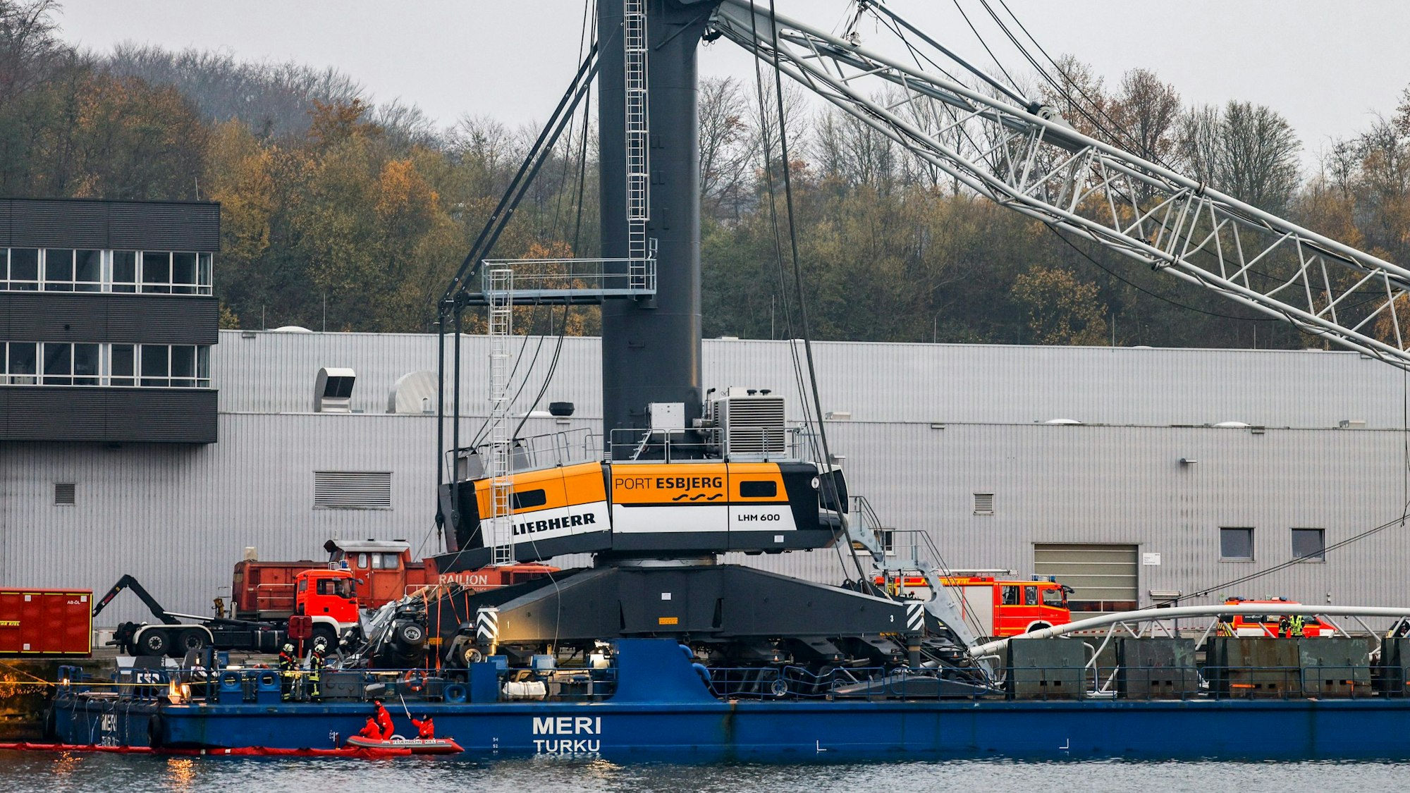 Einsatzkräfte der Feuerwehr arbeiten an dem beschädigten Kran.