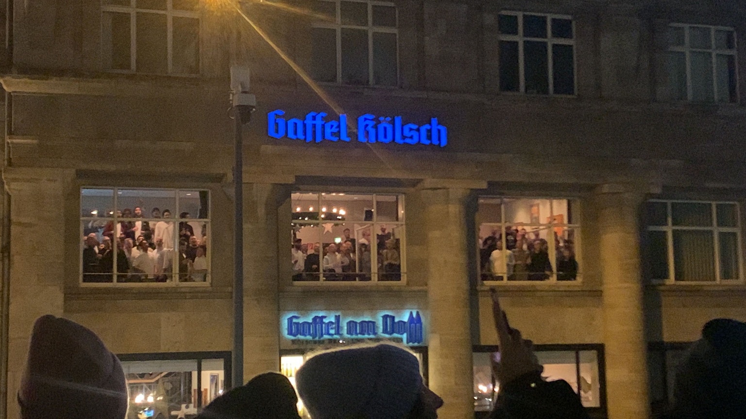 Der Chor gibt ein Adventskonzert im Gaffel am Dom und besingt über die geöffneten Fenster Passanten auf der Kölner Domplatte.