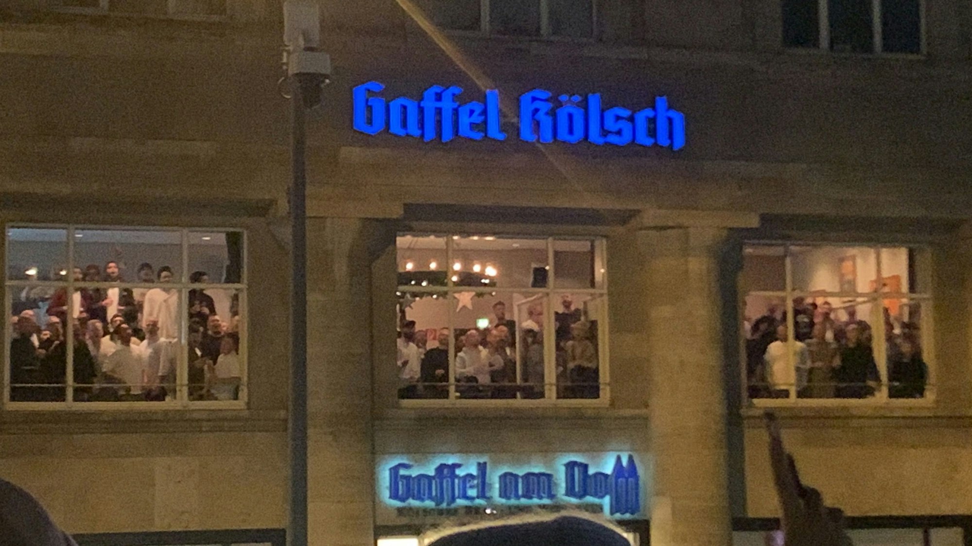 Der Chor gibt ein Adventskonzert im Gaffel am Dom und besingt über die geöffneten Fenster Passanten auf der Kölner Domplatte.