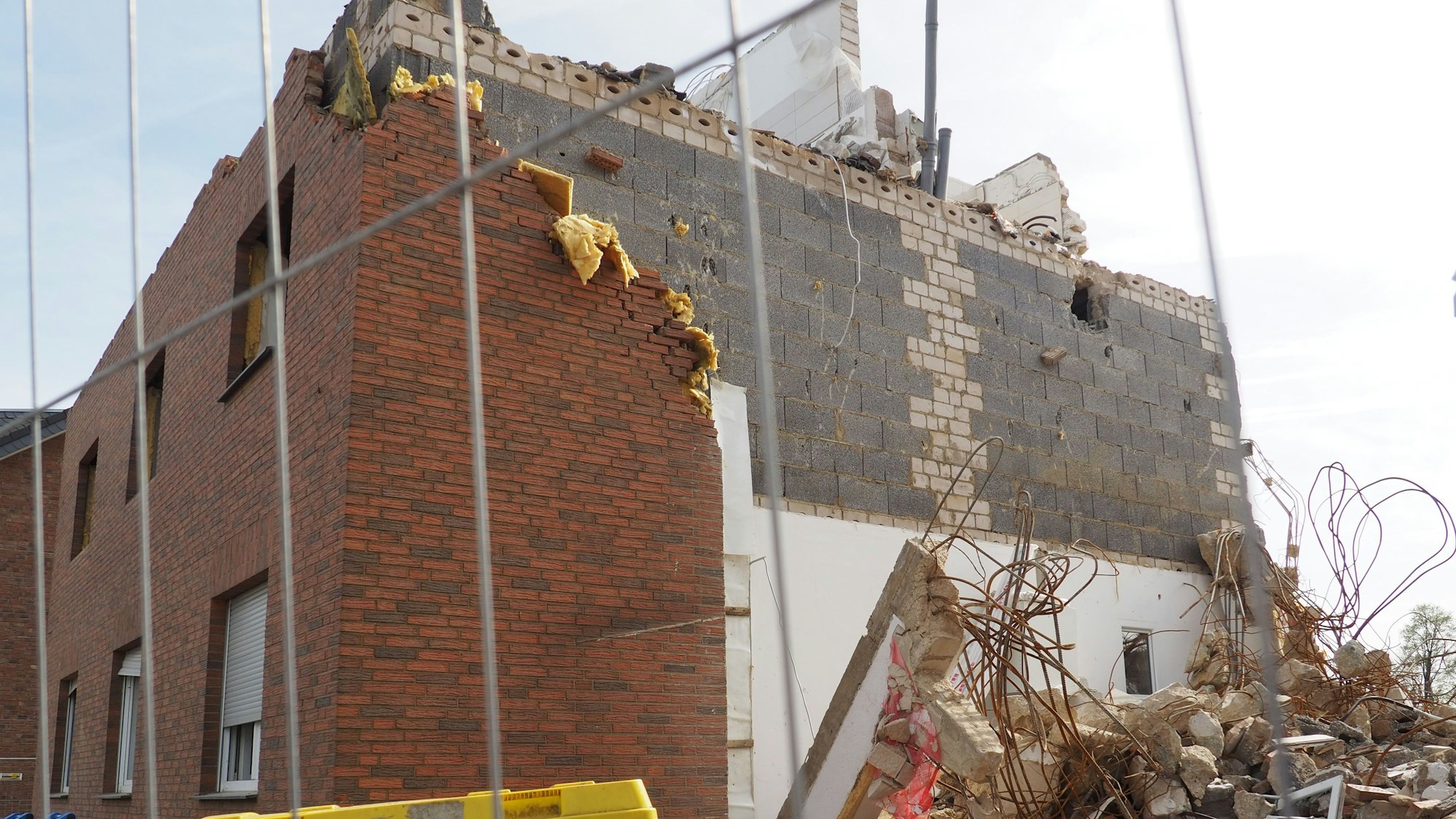 Ein zerstörtes Haus nach der Flut, davor steht ein Bauzaun.