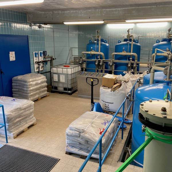 Eine Halle, in der mehrere große Tanks stehen. Im Vordergrund stehen Paletten.