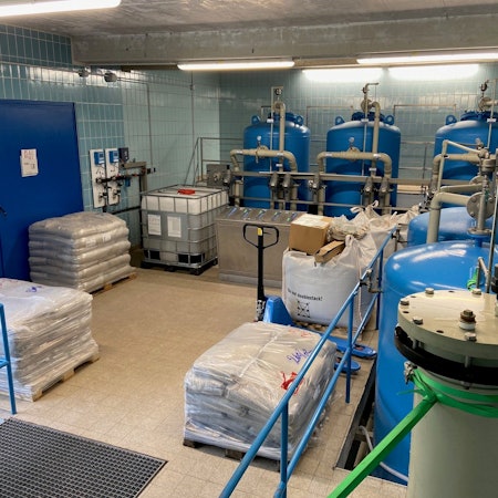 Eine Halle, in der mehrere große Tanks stehen. Im Vordergrund stehen Paletten.