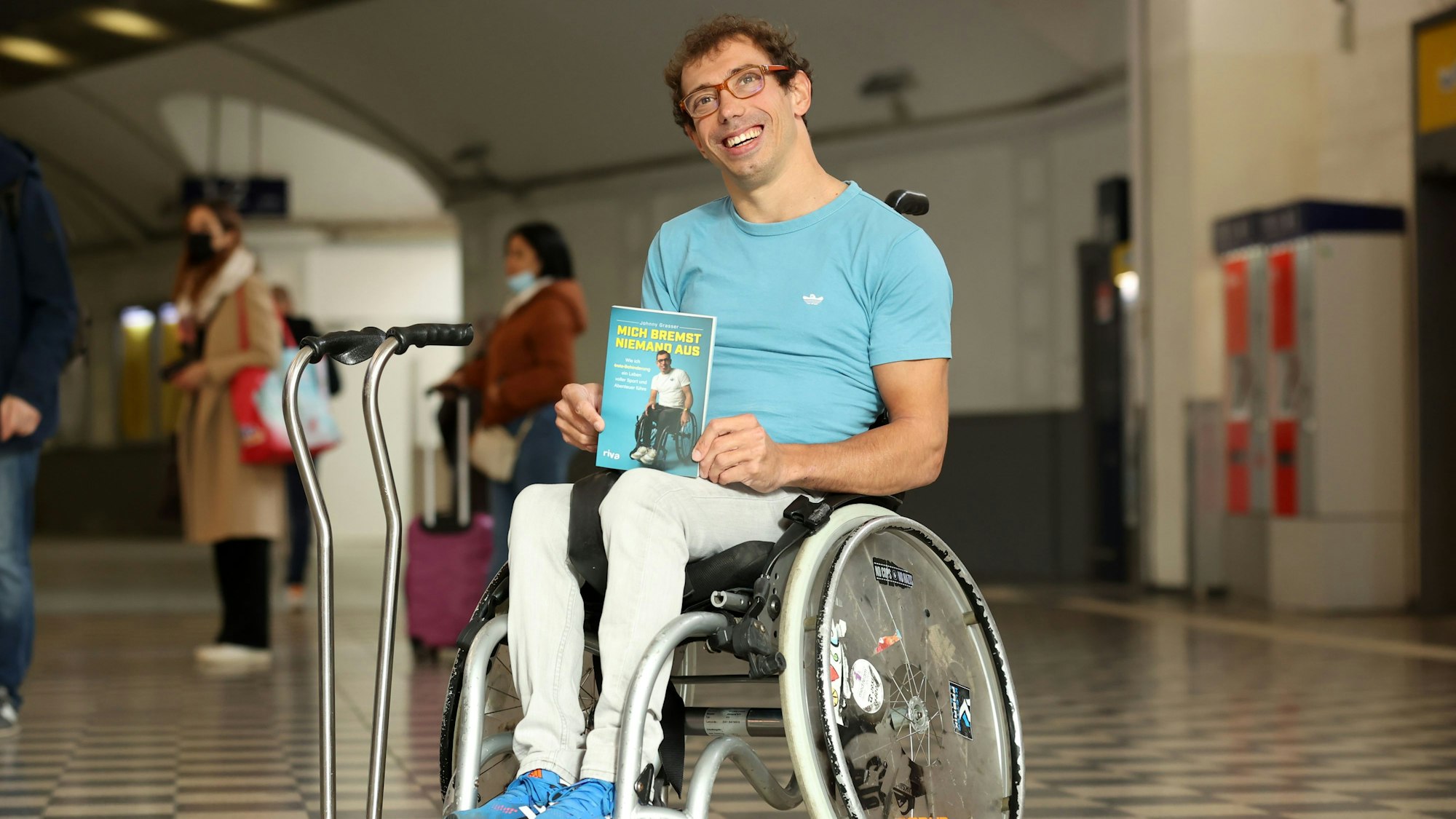 Johannes Grasser sitzt in seinem Rollstuhl und hält sein Buch „Mich bremst niemand“ aus in seinen Händen.