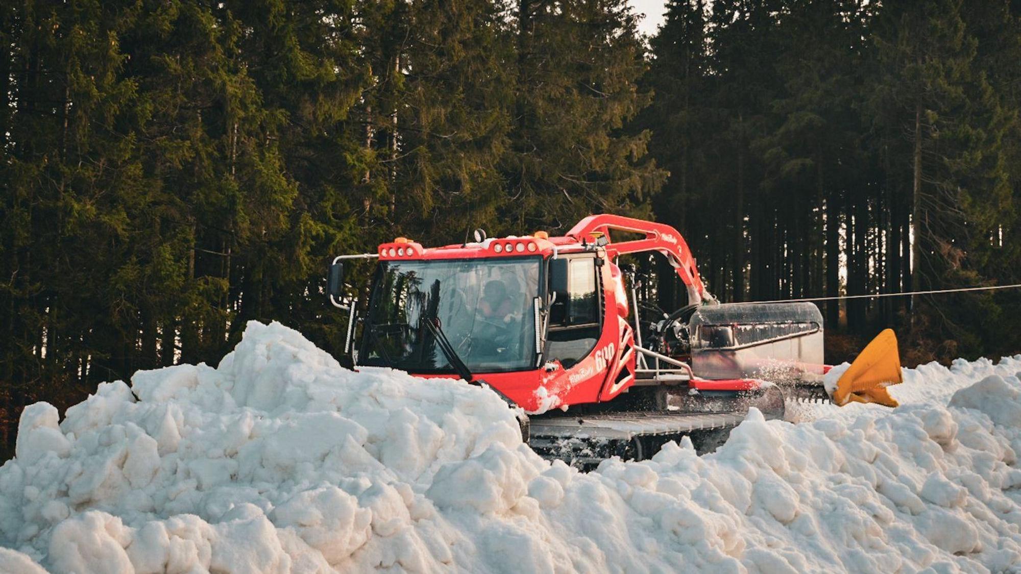 Nordrhein-Westfalen, Winterberg: Eine Pistenraupe verteilt im Skiliftkarussell technisch erzeugten Schnee auf einer Piste.