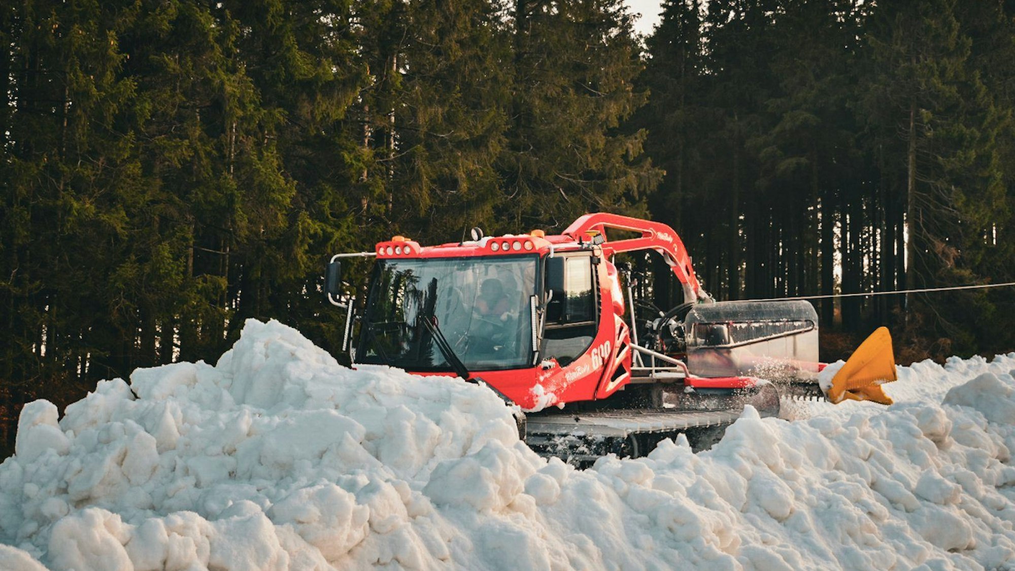 Nordrhein-Westfalen, Winterberg: Eine Pistenraupe verteilt im Skiliftkarussell technisch erzeugten Schnee auf einer Piste.