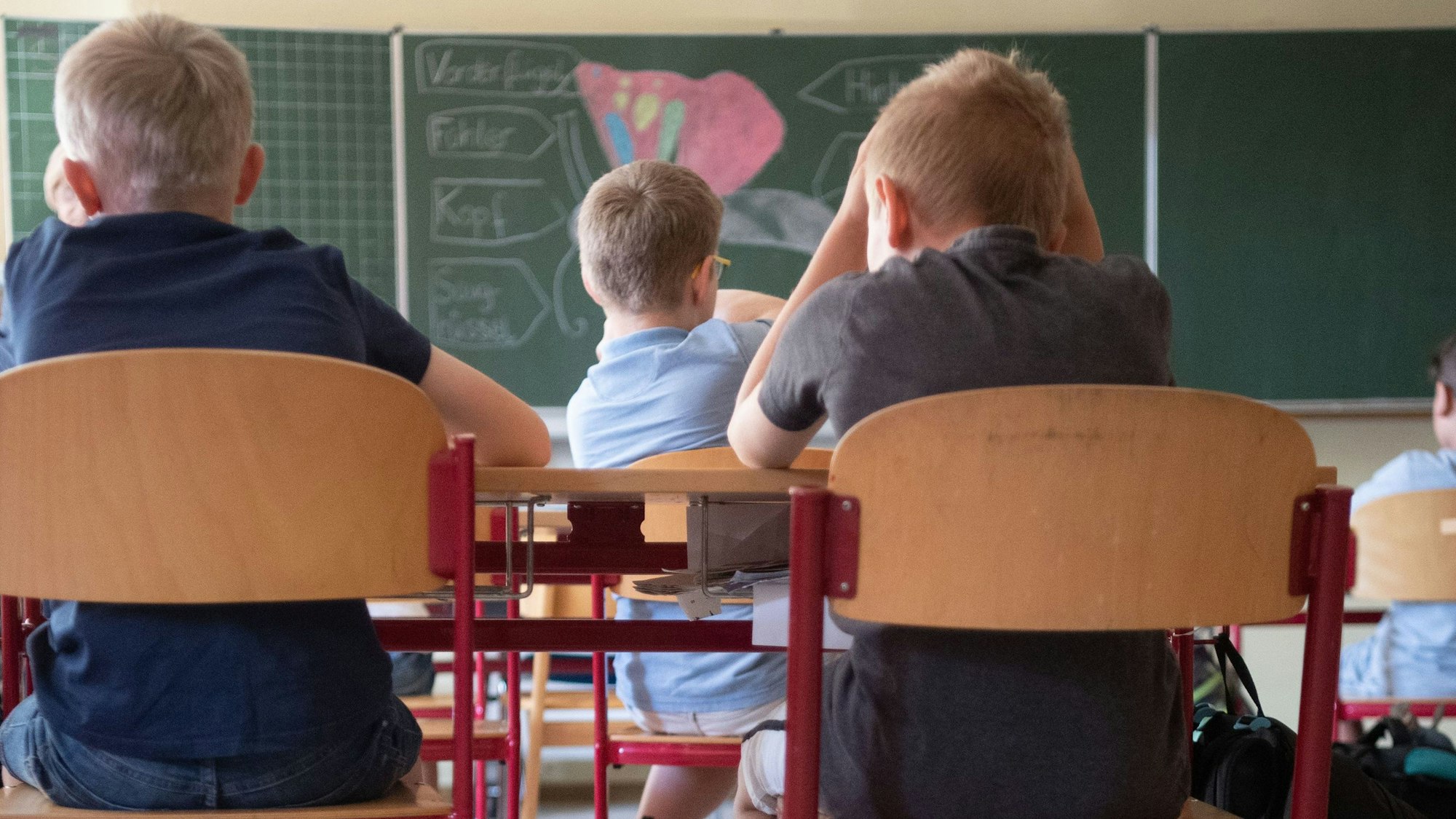 Schülerinnen und Schüler sitzen nebeneinander im Klassenraum einer Grundschule.