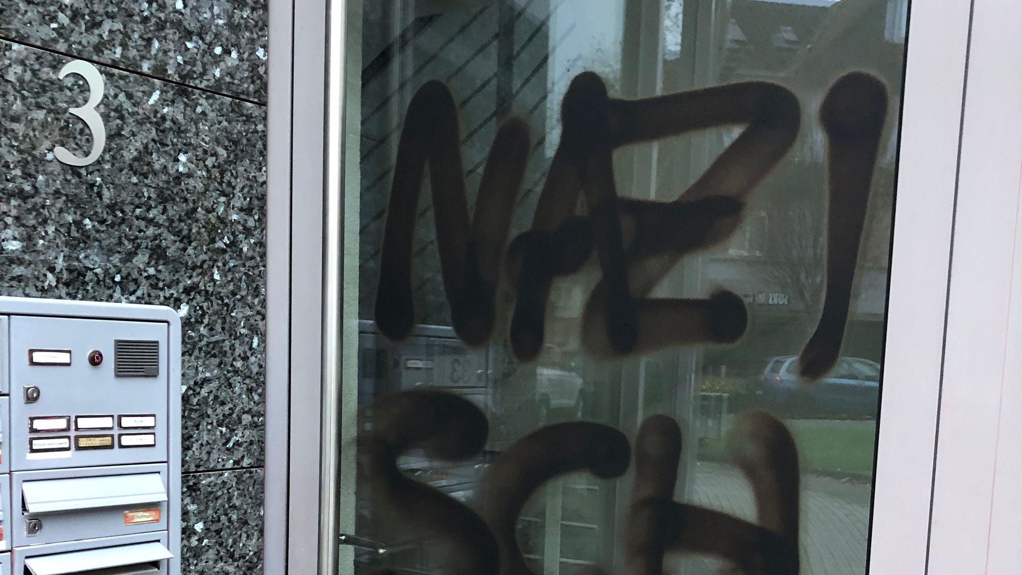 Eine Bürotür, darauf zu sehen in schwarzer Farbe: der Schriftzug „Nazischwein“.