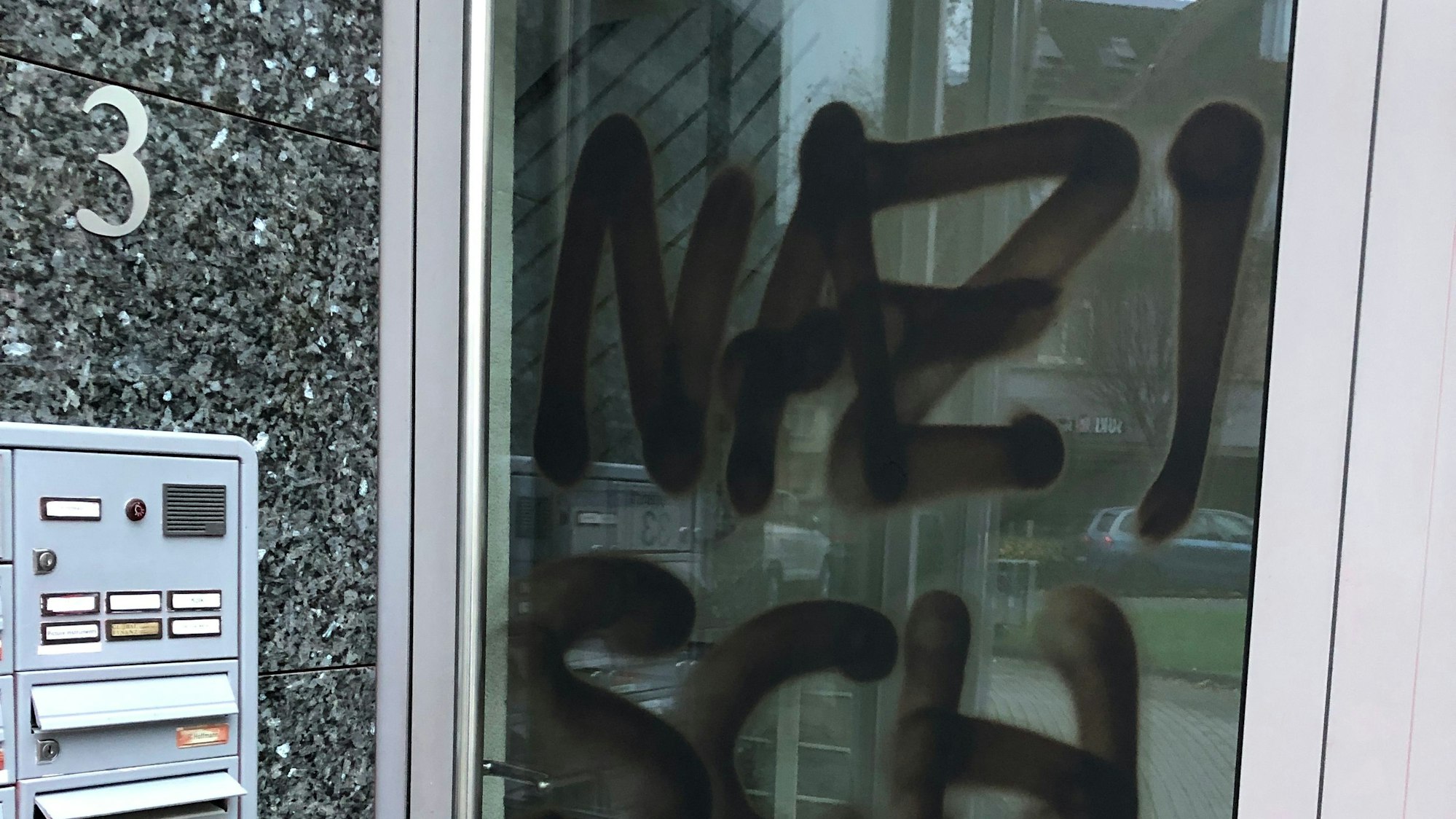 Eine Bürotür, darauf zu sehen in schwarzer Farbe: der Schriftzug „Nazischwein“.