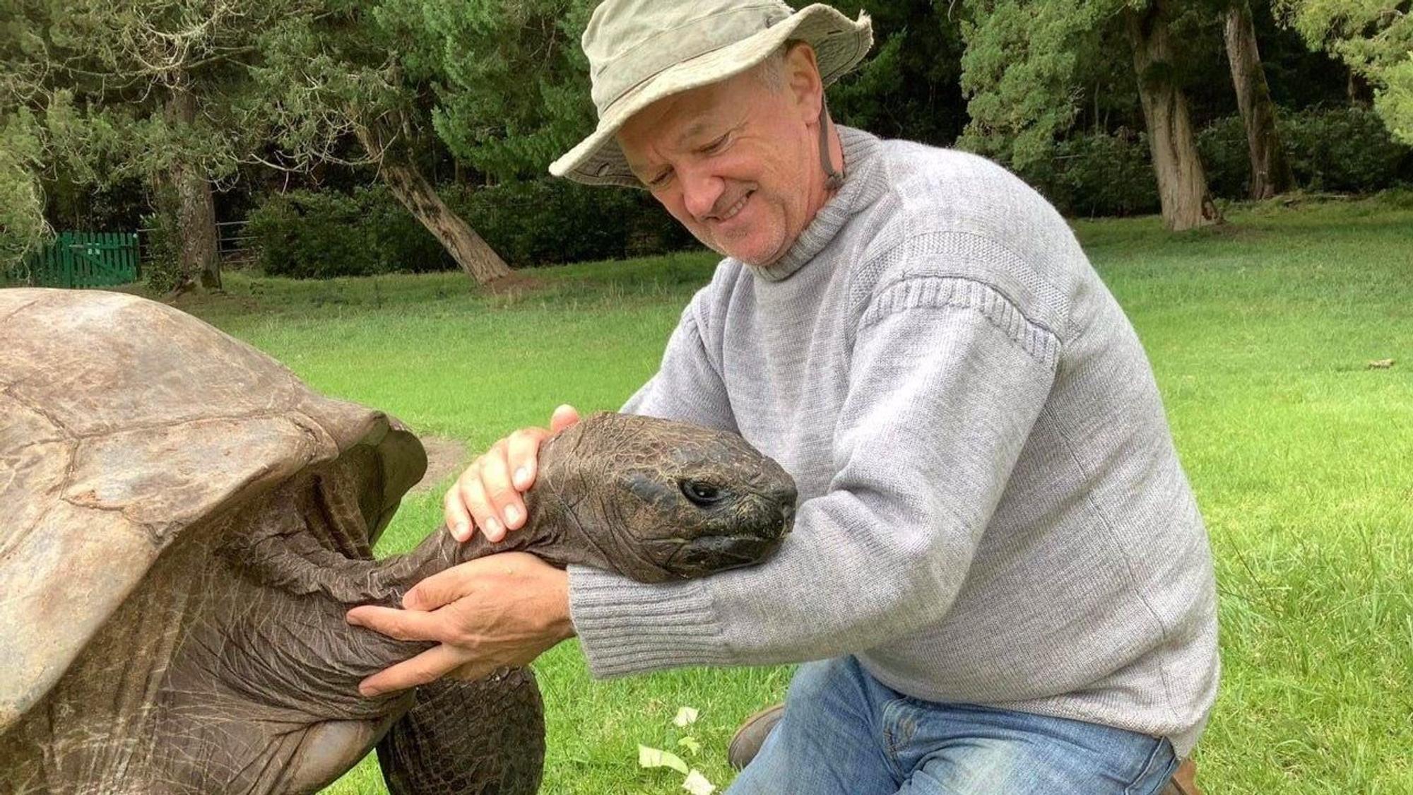 Jonathan (190), die älteste Schildkröte der Welt, wird im Garten der Gouverneurs-Residenz auf der Insel St. Helena von seinem Pfleger Joe Hollins gestreichelt.