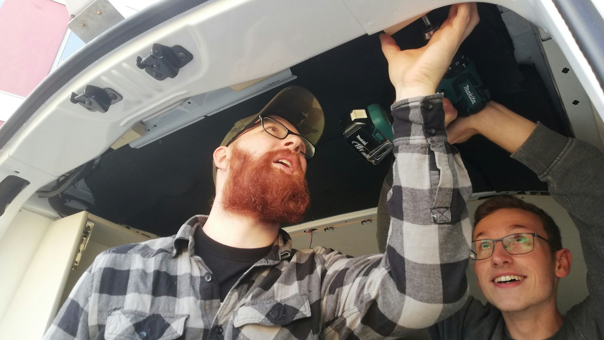 Zwei Tischlerazubis des Berufskollegs Bergisch Gladbach schrauben an der Innenseite des Bergisch Gladbacher Kältebusses.