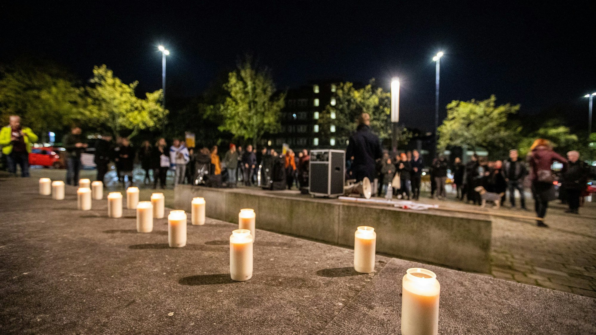 Kerzen stehen bei einer Mahnwache an der Synagoge in Essen auf dem Boden.